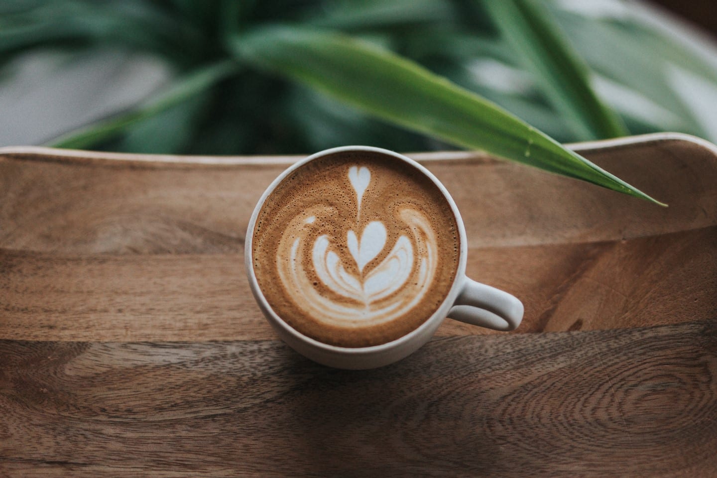 Friendship Market - Cafe latte with milk-foam artwork on a wooden tabletop
