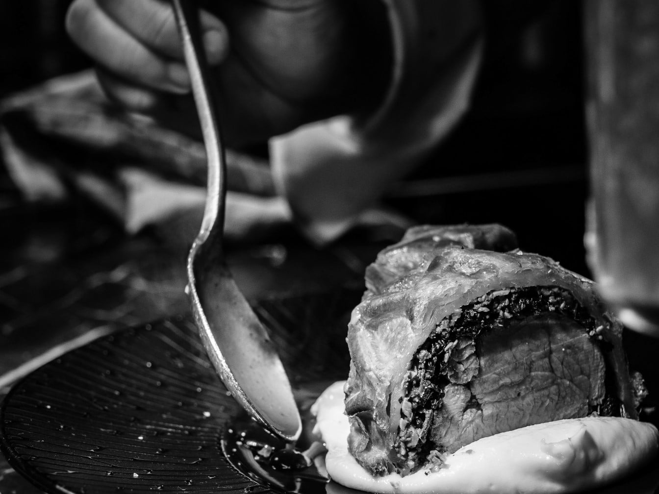 Chef adding finishing touches to a slice of beef wellington on mashed potatoes