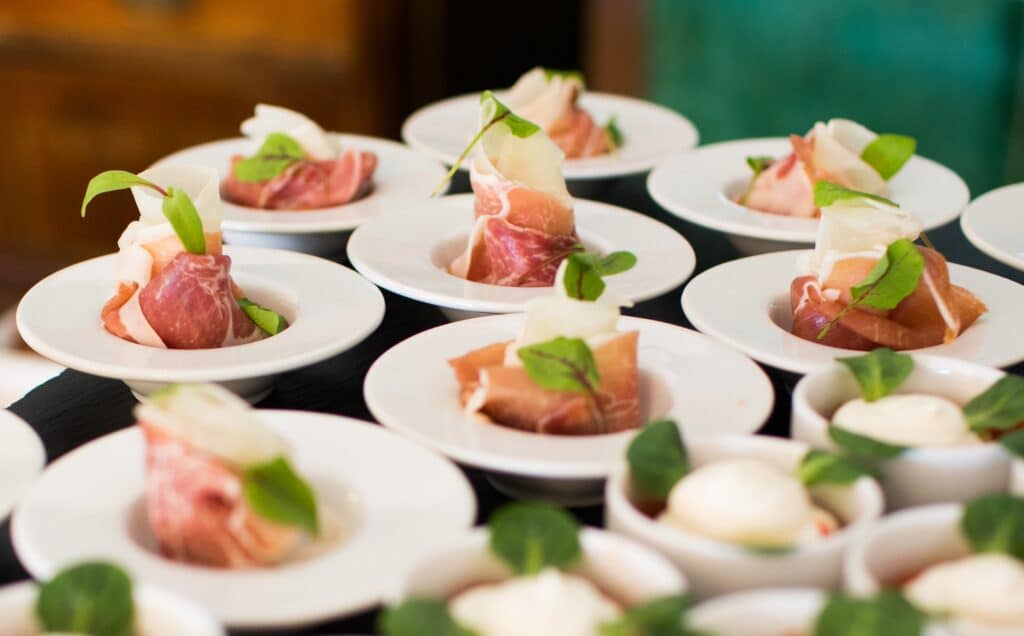 Close up of white bowls with meat and cheese wrapped together with leaves as garnish