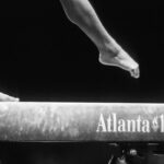 Close-up of a gymnast's feet on a balance beam with "Atlanta 1996" text, capturing the elegance of Olympic Games—a precision akin to navigating the focus required in Type I Meeting Rooms.