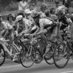 Cyclists compete in a road race, as if seamlessly navigating through a bustling Type I Meeting Room, surrounded by enthusiastic spectators.