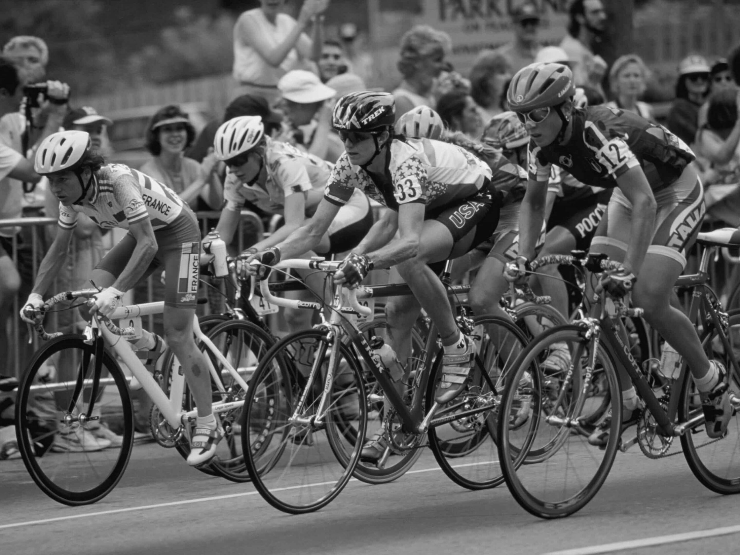 Cyclists compete in a road race, as if seamlessly navigating through a bustling Type I Meeting Room, surrounded by enthusiastic spectators.