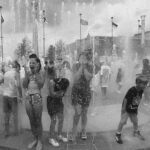 Children playing and laughing in an outdoor water fountain on a sunny day, their joy reminiscent of carefree moments captured in the GSU Digital Collections.