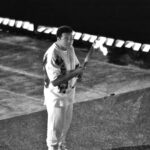 A person in sports attire, embodying the spirit of Sportfolio, holds a lit torch while standing on a sectioned pavement at night.