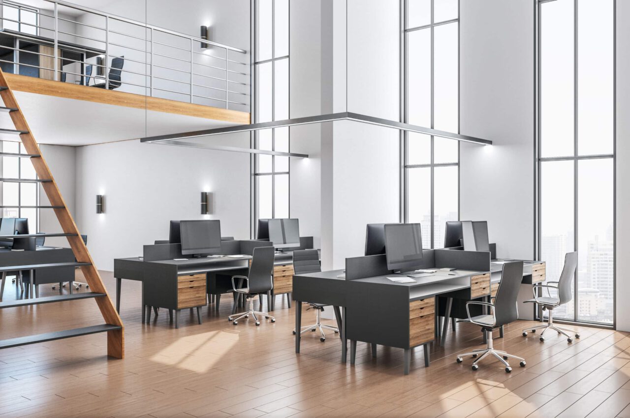 A modern, open office space with multiple desks and chairs, large windows, mezzanine level, and a wooden floor.