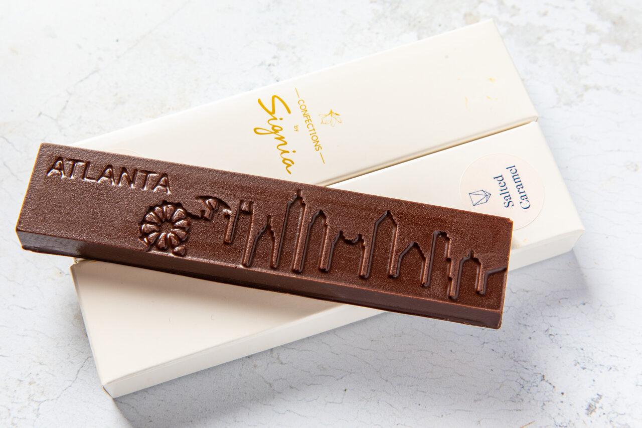 A chocolate bar with "ATLANTA" and the city skyline embossed on it rests on a white box labeled “Salted Caramel,” capturing the sweet spirit of Friendship Market.