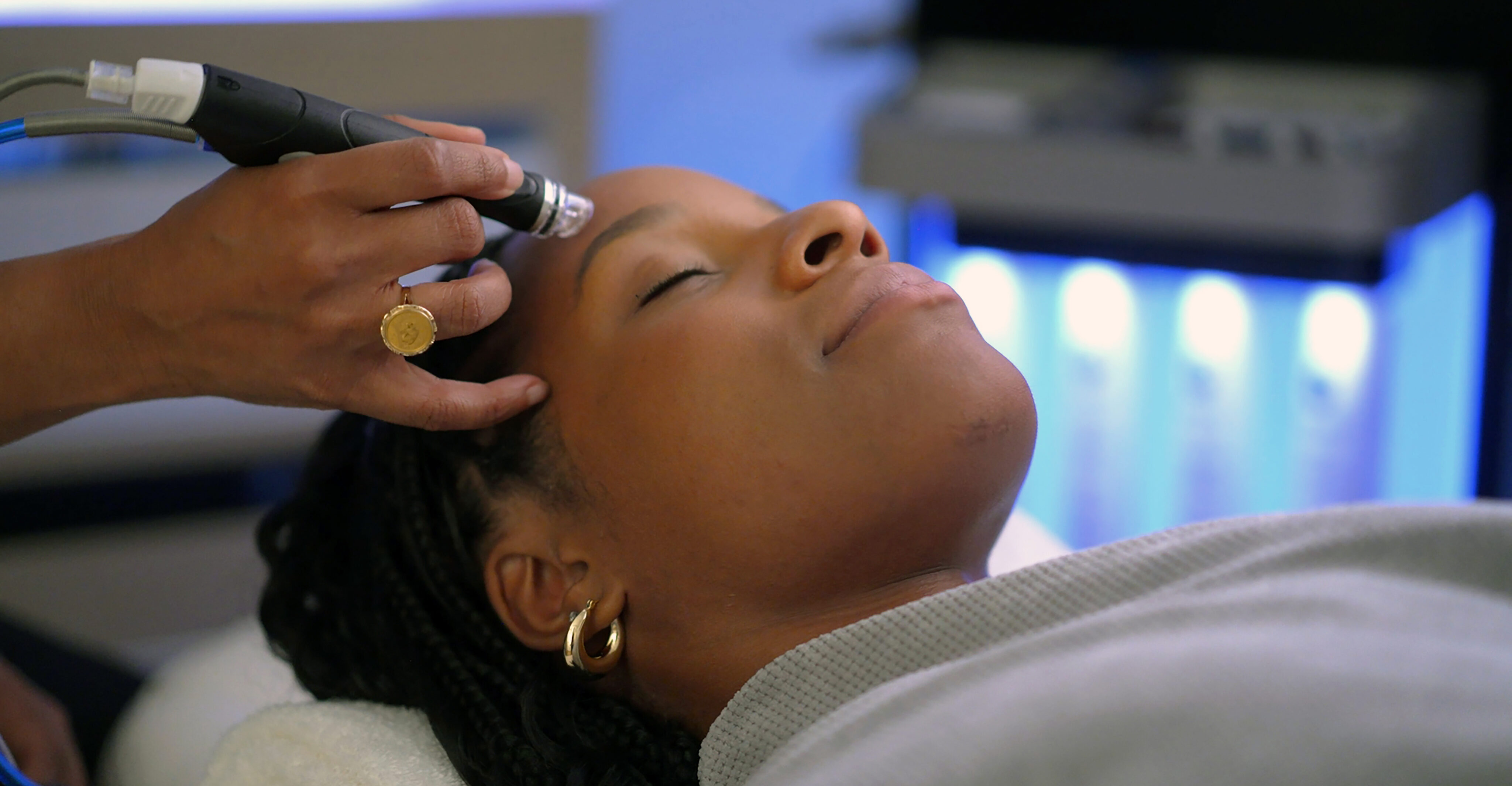 A person enjoys a relaxing facial treatment with the Beauty Bar hand-held device at Signia Spa, lying down with eyes closed.